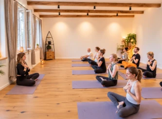 Gruppe bei einer gemeinsamen Yoga-Einheit in einem hellen Seminarraum